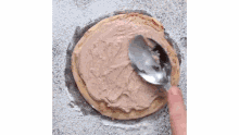a person is using a spoon to spread chocolate frosting on a pancake .