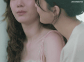 a woman whispering into another woman 's ear with the words lingormgifss visible in the corner