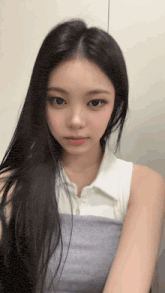 a young woman with long black hair is wearing a white shirt