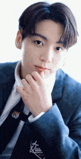 a close up of a young man wearing a suit and tie with a hand on his chin