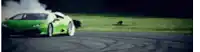 a green sports car is drifting on a track and smoke is coming out of the tires .