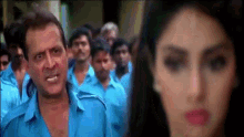 a man in a blue shirt is standing in front of a woman in a red dress .