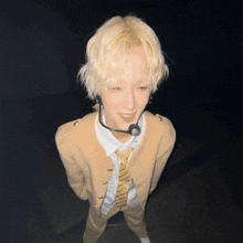 a man with blonde hair is wearing a tie and a microphone around his neck
