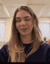 a woman wearing a blue shirt and a cross necklace