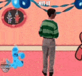 a man in a green and white striped shirt is standing in front of a pink wall with balloons and ribbons .
