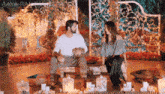 a man and a woman are sitting at a table with candles and flowers .