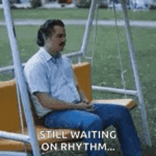 a man is sitting on a swing in a park and waiting for something .