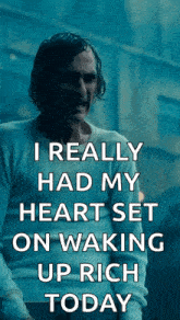 a man in a white shirt is holding a sign that says i really had my heart set on waking up rich today