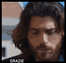 a man with long hair and a beard has the word grazie above his head