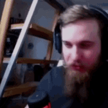 a man with a beard is wearing headphones while holding a microphone .