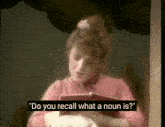 a woman in a pink shirt is reading a book and asking " do you recall what a noun is "