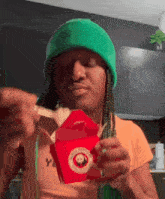 a person wearing a green beanie is eating a box of panda express food