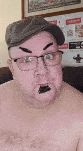 a shirtless man wearing glasses and a hat has a sticker on his eyebrow that says ' subscribe ' on it