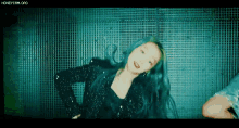 a woman with blue hair is dancing in front of a wall .