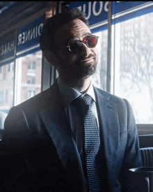 a man in a suit and tie is sitting in front of a window with a sign that says dimer