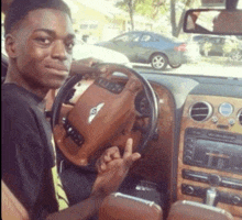 a young man is sitting in a bentley car and giving the middle finger