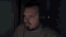 a man with a beard is wearing headphones and looking at a computer screen in a dark room .