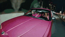 two women are driving a pink car with the dor brothers on the hood