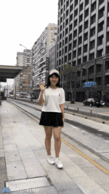 a girl stands on a sidewalk in front of a building that has the word momento on it