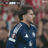 a man in a blue adidas jersey stands in front of a scoreboard that says ath 0-3 mun