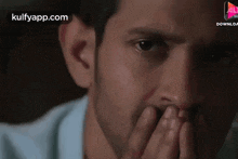 a close up of a man covering his mouth with his hand ..