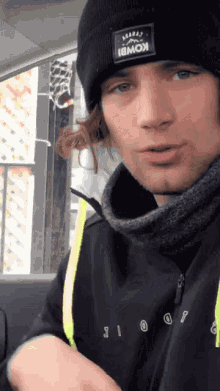 a young man wearing a black beanie with the word kombi on it