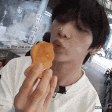 a young man is eating a piece of food with a sticker on the wall that says ' ecamples '