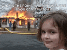 a little girl is standing in front of a burning house ..