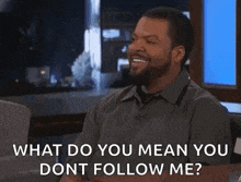 ice cube is smiling while sitting at a table and talking to a woman .