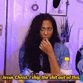 a woman sitting at a table with a bottle of water and the words jesus christ i ship the shit out of this