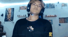 a young man wearing headphones and a black shirt with the letter j on the sleeve