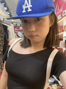 a woman wearing a blue la hat is taking a selfie