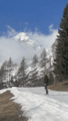 a blurred image of a snowy road with trees and mountains in the background