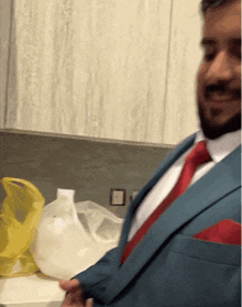a man in a blue suit and red tie has a red pocket square in his pocket