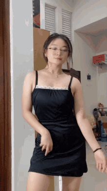 a woman in a black dress and glasses is dancing