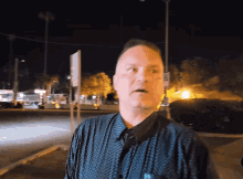 a man in a polka dot shirt stands in front of a street sign that says no parking