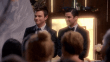 two men in tuxedos are standing next to each other at a wedding
