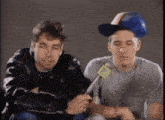 two young men are sitting next to each other and one of them is holding a microphone .
