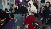 a group of people are gathered in a room with a man wearing a delta hoodie