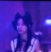 a woman wearing a hat and a bow is standing in front of a purple light .