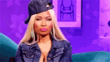 a woman wearing a hat and a denim jacket is sitting on a blue couch