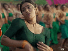 a woman in a green blouse is standing in front of a crowd of people ..