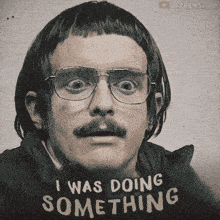a man with glasses and a mustache wears a shirt that says i was doing something