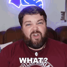 a man with a beard wearing a red shirt that says what