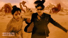 two women running in a desert with #beetlejuice written on the bottom right