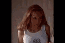 a young woman in a blue tank top is standing in a room .