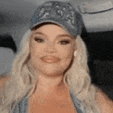 a woman is wearing a baseball cap and smiling while sitting in the back seat of a car .