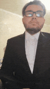 a man with glasses and a beard wearing a suit