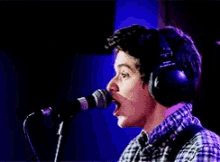 a man is singing into a microphone with headphones on