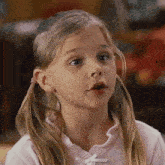 a little girl with pigtails is wearing a pink shirt